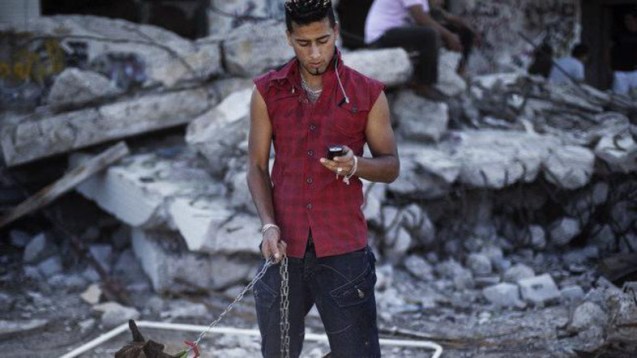 Um jovem lê mensagens no seu telemóvel, em Trípoli, 28 de Outubro de 2011. A Líbia planeia lançar em 2014 um concurso para o funcionamento da primeira operada privada de telecomunicações. © AFP