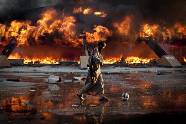 Um rebelde líbio joga à bola num cenário de guerra, em 2012. © Philippe de Poulpiquet | Photographie.com