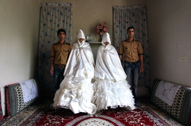 Iranian grooms, Javad Jafari, left, and his brother, Mehdi, right, pose for photographs with their brides, Maryam Sadeghi, second left, and Zahra Abolghasemi, who wear their formal wedding dresses prior to their wedding in Ghalehsar village, about 220 mi (360 km) northeast of the capital Tehran, Iran, on July 15, 2011. @AP Photo/Vahid Salemi)