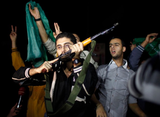 A Palestinian gunman kisses his rifle as he celebrates what he says is a victory over Israel after an eight-day conflict in Gaza City
