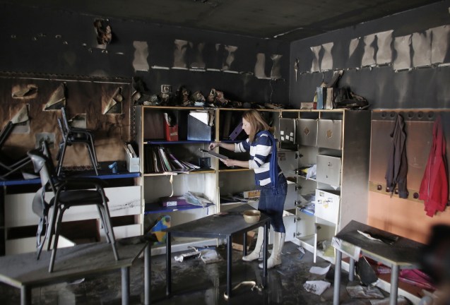 A woman inspects the damage on the aftermath of an arson attack that targeted first-grade classrooms at a Jewish-Arab school in southern Jerusalem. Scrawled on the walls were offensive slogans in Hebrew reading 'Death to Arabs' and 'There's no coexistence with cancer'. © AFP
