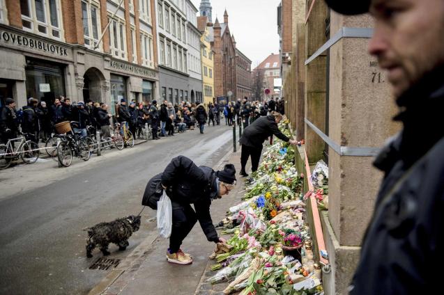 People lay flowers outside a synagogue where an attack took place in Copenhagen, Sunday, Feb. 15, 2015. Danish police shot and killed a man early Sunday suspected of carrying out shooting attacks at a free speech event and then at a Copenhagen synagogue, killing a Danish documentary filmmaker and a member of the Scandinavian country's Jewish community. Five police officers were also wounded in the attacks. © Rumle Skafte | AP|DENMARK OUT