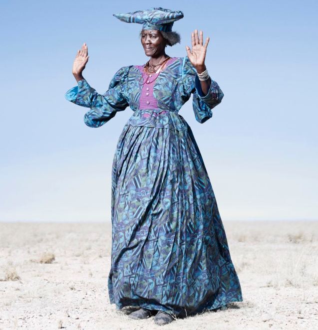 Costume drama: Herero woman in blue dress in cow dance pose © Jim Naughten 