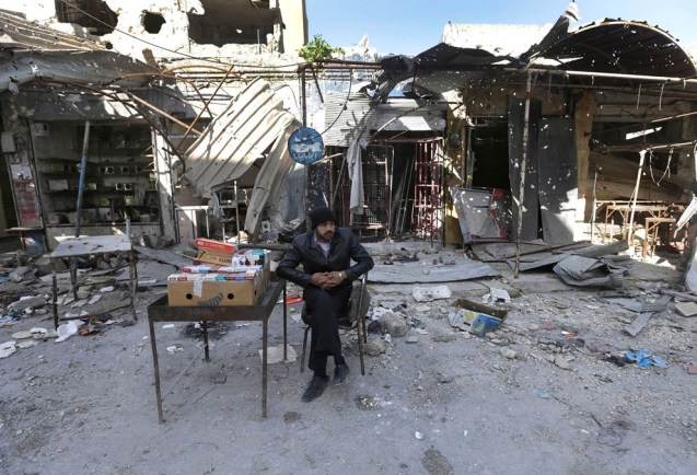 A Syrian street vendor who sells cigarette boxes, sits in front of destroyed shops which were damaged by the shelling of the Syrian forces, at Maarat al-Nuaman town, in Idlib province, on February 26, 2013. Syrian rebels battled government troops near a landmark 12th century mosque in the northern city of Aleppo on Tuesday, while fierce clashes raged around a police academy west of the city, activists said. © Hussein Malla | AP