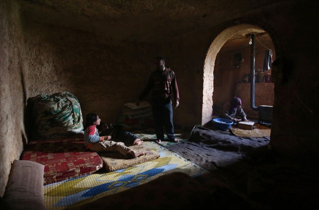 A father speaks with his children in an underground Roman tomb which he uses with his family as shelter from Syrian government forces, at Jabal al-Zaweya, in Idlib province, on February 28, 2013. The ancient sites are built of thick stone that has already withstood centuries, and are often located in strategic locations overlooking towns and roads. © Hussein Malla | AP