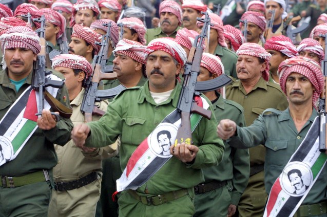 Membros do Baas desfilam com Kalashnikov e fotos do executao ditador Saddam Hussein, em 8 de Fevereiro, durante celebrações do 39º aniversário do golpe que levou o partido ao poder. A dissolução do Baas, ordenada pelos "administradores" americanos, após a invasão de 2003, levou a que muitos militantes e antigos oficiais iraquianos se juntassem ao Daesh, © Ramzi Haidar | AFP | Getty Images